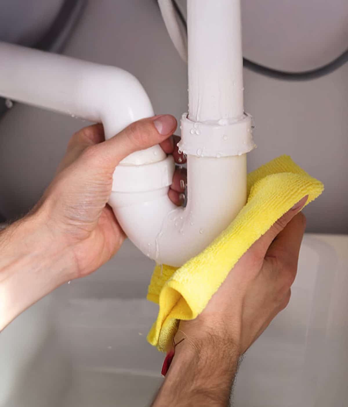 plumber fixing leaking pipe under sink